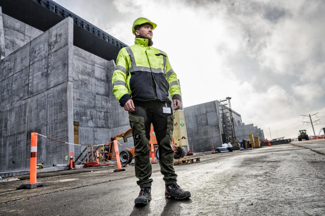 Byggekoordinator_Fra praktikant til produktionsleder Mandlig byggekoordinator står foran byggeri