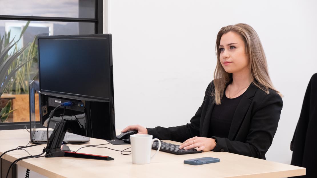 Kvinde står og arbejder ved computer