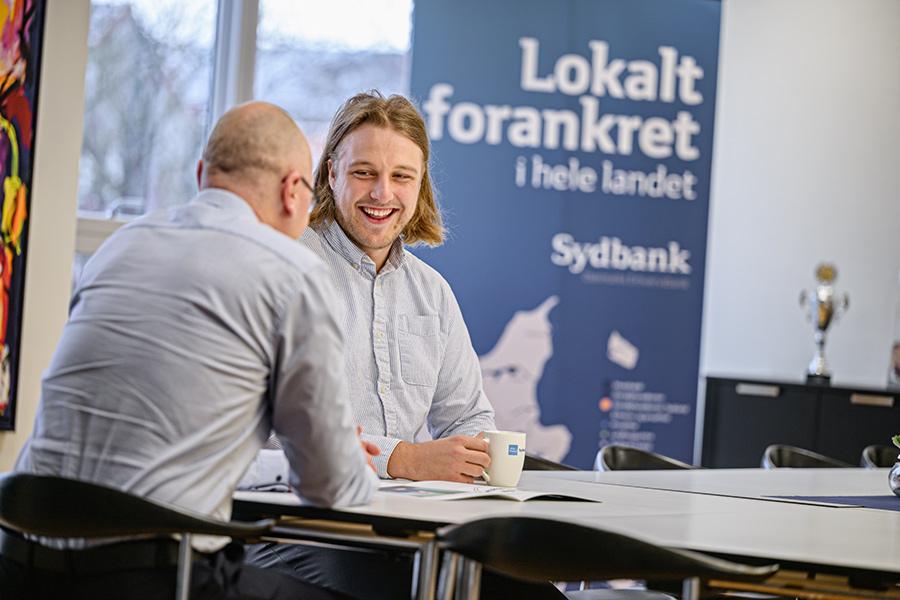 Finansbachelor i praktik ved Sydbank Erhverv To mænd sidder og snakker ved et bord
