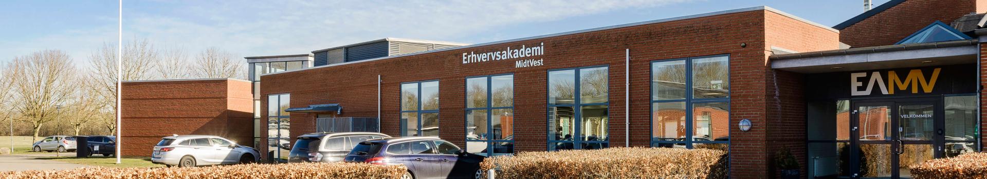 Læs om vores afdeling i Holstebro Tre smilende studerende sidder og arbejder sammen ved et bord